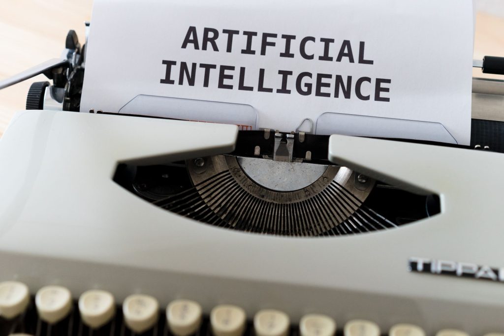 Type writer with a piece of paper that says 'artificial intelligence' on it